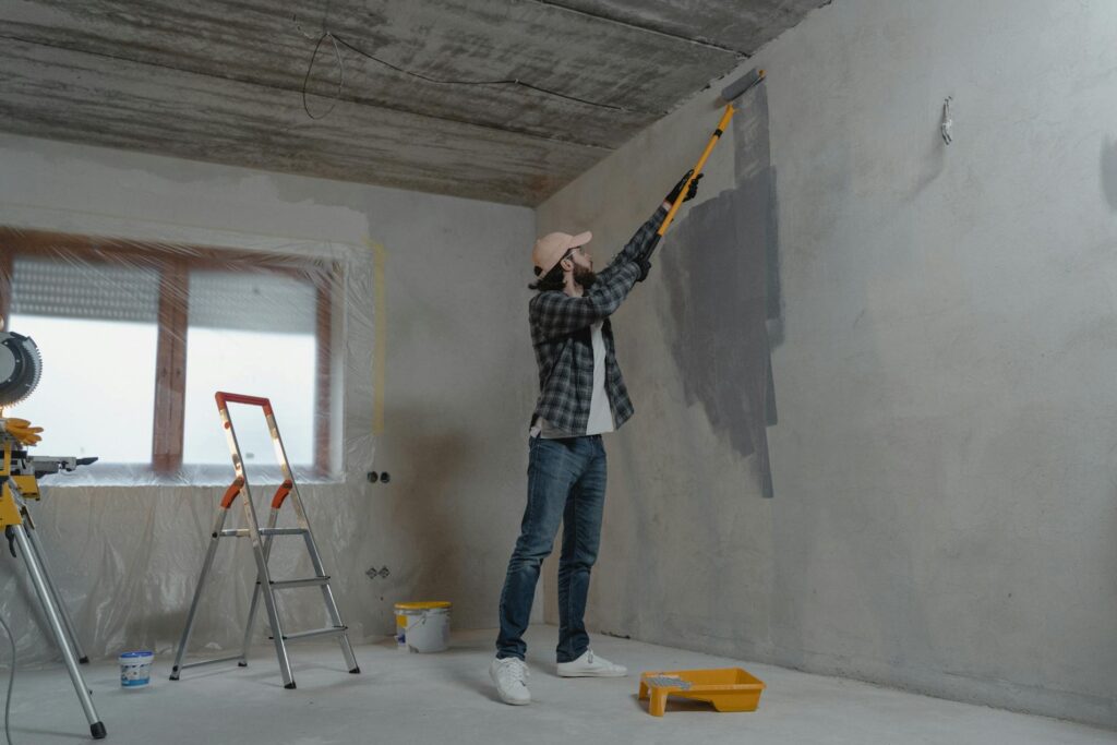 Man repainting a wall to improve the appearance of a home, a common step when selling a house in poor condition.